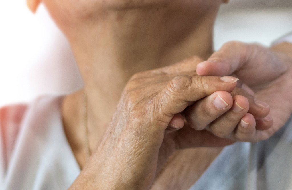 Alguien agarrando la mano de un envejeciente como un gesto de apoyo
