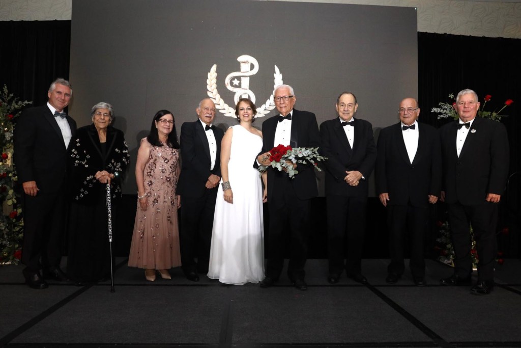 El doctor Jaime Rivera Dueño (al centro con ramo de flores), junto a Lorena Casado Díaz presidenta de la Junta de directores y productora ejecutiva del Salón de la Fama de la Medicina Puertorriqueña- acompañados por varios de los miembros de este organismo.