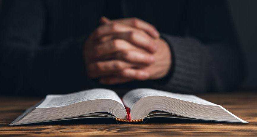 Manos orando frente a la Biblia